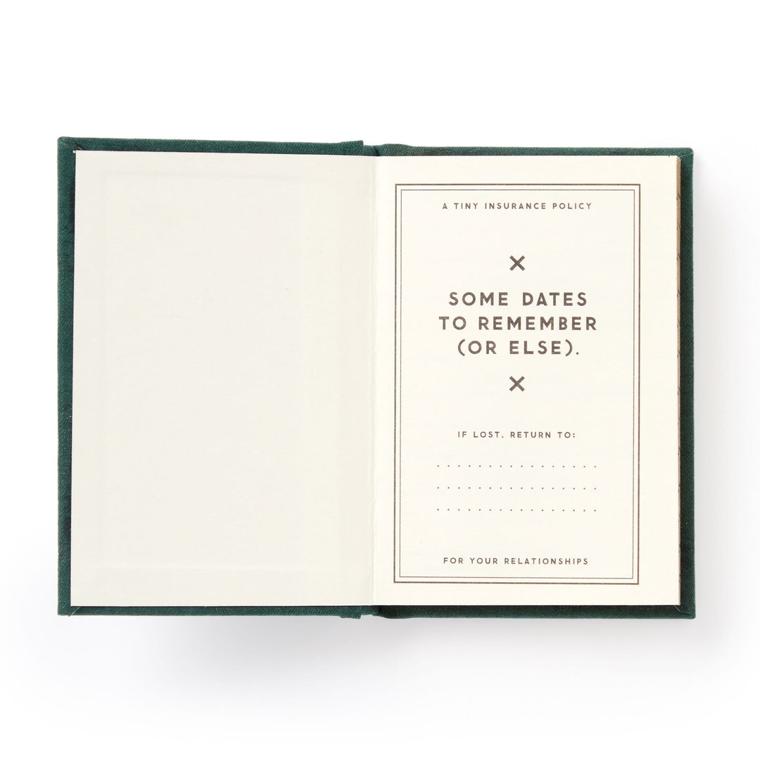 A hard-bound Brass Monkey Dates People Get Mad If I Forget Tiny Diary lies open with gilded pages: one blank, the other titled A Tiny Insurance Policy—Some Dates to Remember (Or Else), plus a spot for contact info if lost.