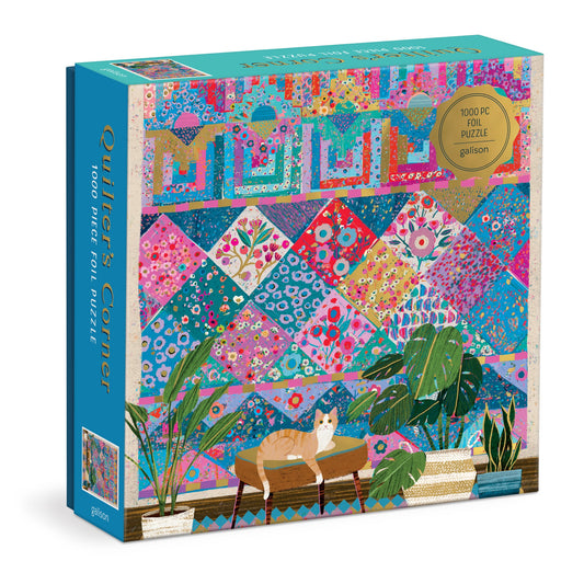 Victoria Ball Quilters Corner 1000 Piece Foil Puzzle features a vibrant quilt tapestry with floral and geometric patterns, a lounging cat, green potted plants, and shines with gold foil accents.