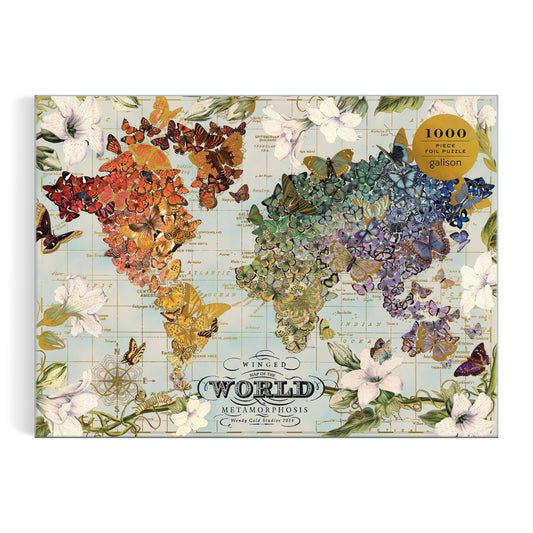 The Wendy Gold Winged Metamorphosis 1000 Piece Foil Puzzle by Wendy Gold features a world map of vibrant butterflies in gradient hues, surrounded by white flowers and green leaves on a light, vintage-style background.