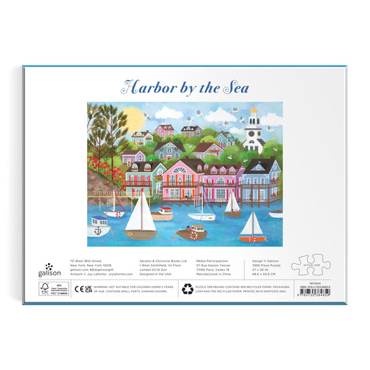 The Joy Laforme Harbor by the Sea 1000 Piece Puzzle showcases a vibrant Nantucket harbor scene with sailboats, colorful houses, trees, and a white church—an ideal addition to any puzzle lover’s collection.