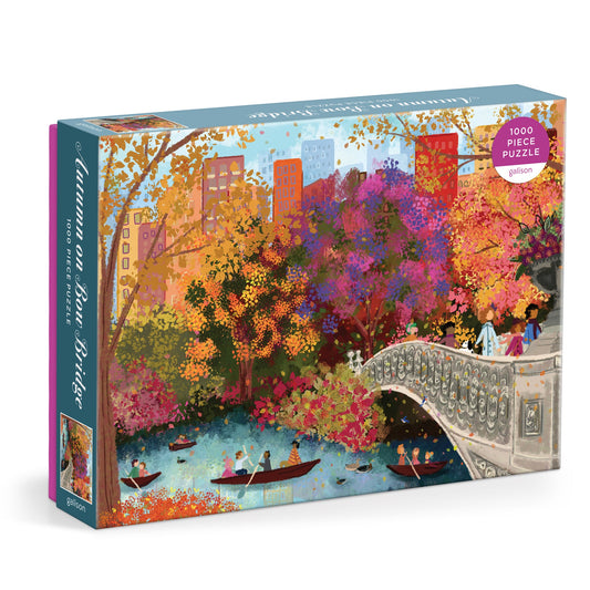 The Joy Laforme Autumn on Bow Bridge 1000 Piece Puzzle by Joy Laforme features vibrant autumn trees in Central Park, with people boating on the lake, strolling across Bow Bridge, and city buildings in the background.