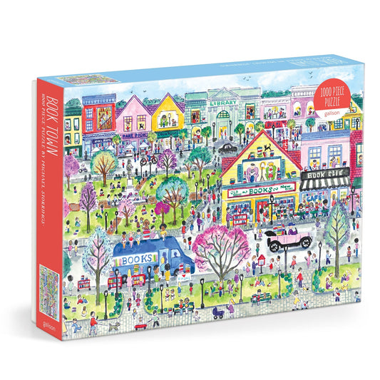 The Michael Storrings Book Town 1000 Piece Puzzle features a vibrant illustrated town with bookstores, a library, people, trees, and cars—perfect for book lovers. Brand: Michael Storrings.