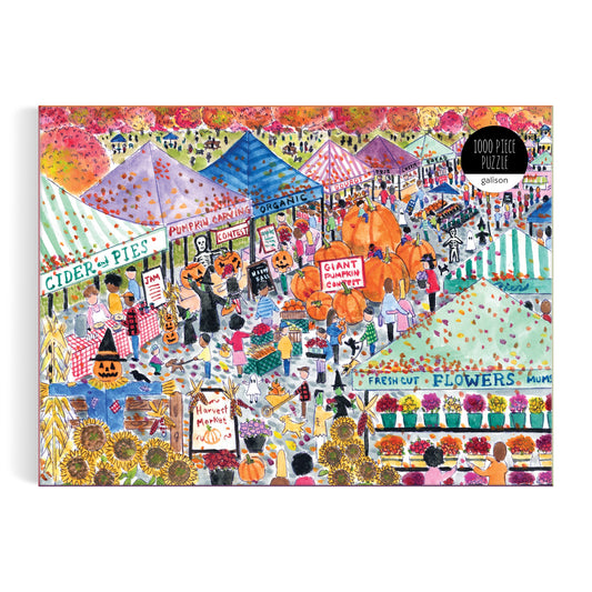 Michael Storrings Harvest Market 1000 Piece Puzzle features a vibrant fall market scene with striped tents, pumpkins, flowers, shoppers, cider and pie signs, organic produce, a pumpkin carving contest, and scattered autumn leaves.