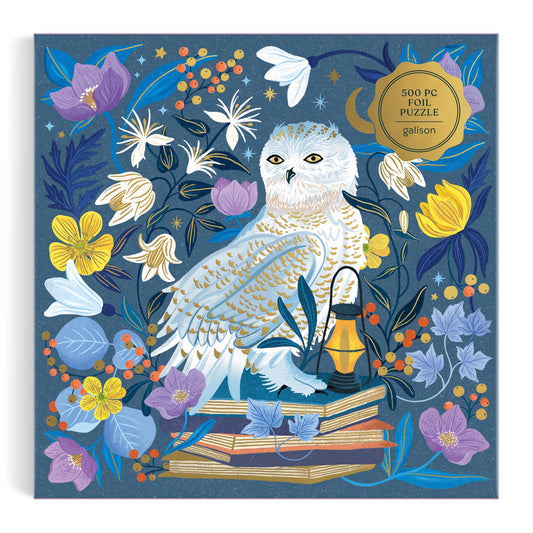 Illustration of a snowy owl on stacked books with vibrant flowers, leaves, and a lantern. A blue, starry backdrop sets the scene for Dawn Cooper’s Celestial Owl 500 Piece Foil Puzzle.