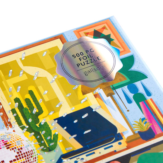 A close-up of the Disco Life 500 Piece Foil Puzzle box by EurekartStudio showcases plants, a disco ball, and abstract decor, with a shiny sticker highlighting its modern foil accents and retro charm.