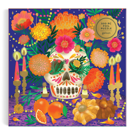 The Ofrenda del Día de Muertos 500 Piece Foil Puzzle by Marisol Ortega features a vibrant sugar skull scene with premium metallic foil accents and gold “500 PC Foil Puzzle” label, honoring Mexican cultural heritage.