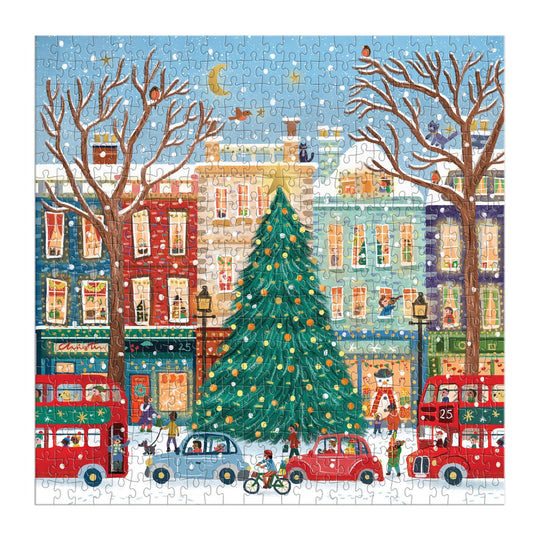 Celebrate the holidays with Laura Watkins’ Tinsel City 500 Piece Foil Puzzle, featuring a lively urban scene with a dazzling Christmas tree, festive lights, double-decker buses, and vibrant city buildings under a clear winter sky.