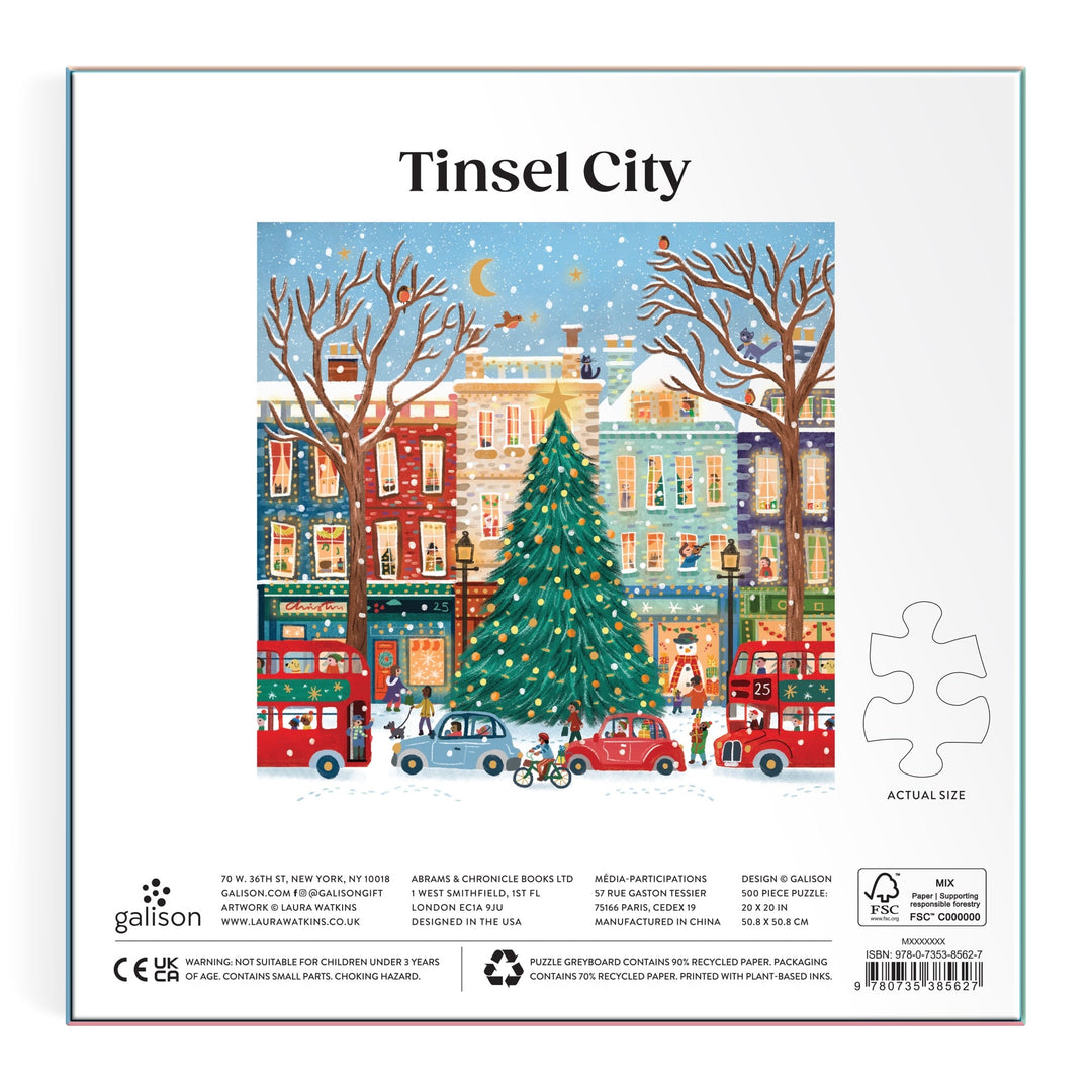 Illustration of a festive city with a big decorated Christmas tree, vibrant buildings, snow, people, and red double-decker buses under a starry sky features on the Tinsel City 500 Piece Foil Puzzle by Laura Watkins.