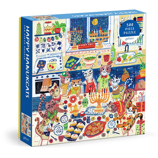 The Anna Ivanir Happy Hanukcats 500 Piece Puzzle features illustrated cats celebrating Hanukkah in a festive kitchen, surrounded by menorahs, food, and decorations.