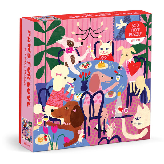 The Paws for Love 500 Piece Puzzle by Anne Bentley showcases whimsical dogs and cats dining at a flower-filled table on a playful pink background.