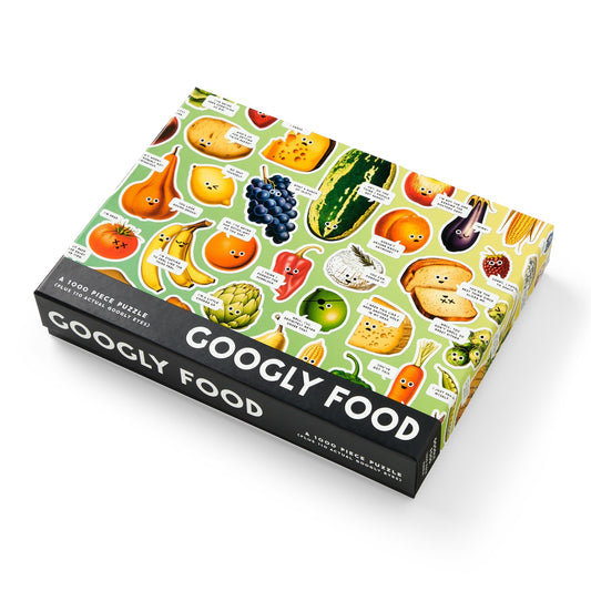 The Googly Food 1000 Piece Puzzle by Brass Monkey features illustrated fruits, veggies, and foods with googly eyes and playful expressions on a vibrant green background.