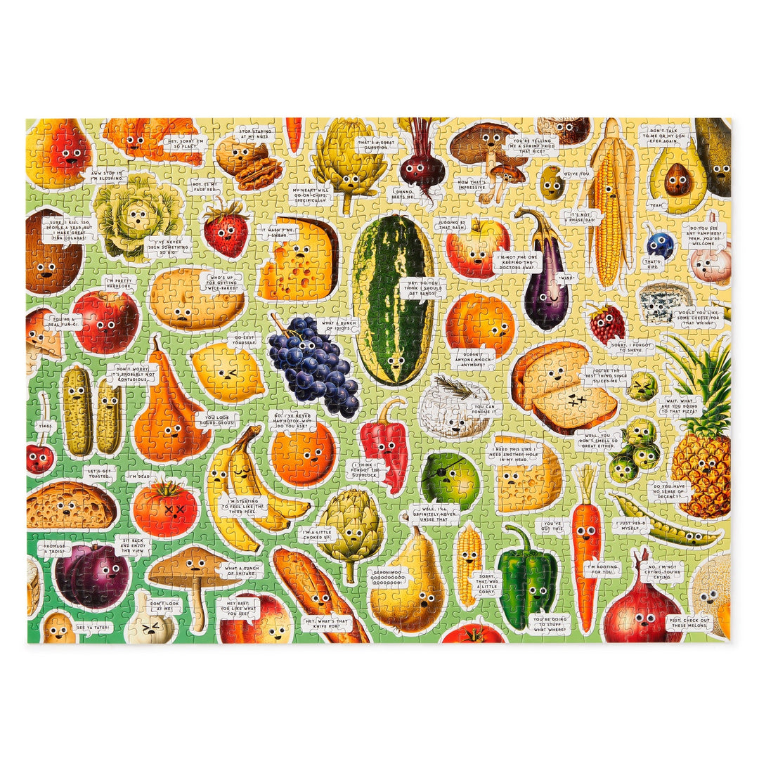 Brass Monkeys Googly Food 1000 Piece Puzzle is a colorful collage of illustrated fruits and veggies with faces and speech bubbles, each sharing funny or punny lines, set against a yellow-to-green gradient background.