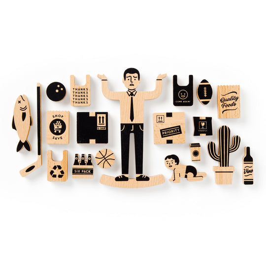 The Brass Monkey One Trip Nick Wooden Balance Game features grocery-themed wooden pieces like shopping bags and a wine bottle, plus fun shapes such as a man shrugging, fish, basketball, recycling symbol, baby crawling, cactus, and more.