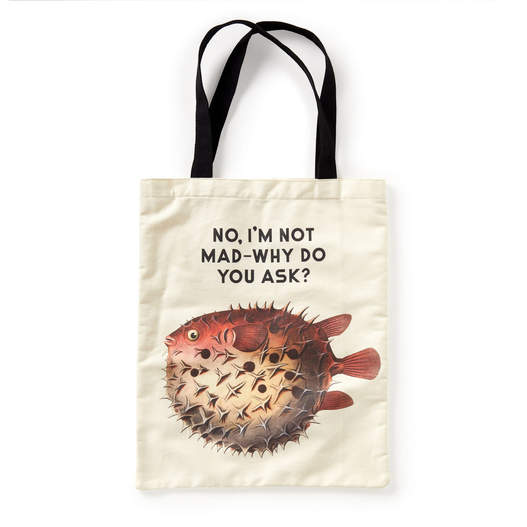 The Brass Monkey Judgy Fish Canvas Tote is a beige bag with black handles, featuring a pufferfish graphic and the funny phrase NO, IM NOT MAD—WHY DO YOU ASK? above the fish.