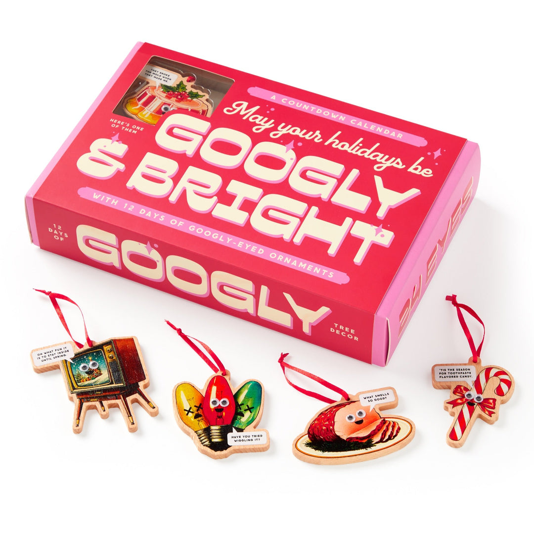 The Brass Monkey Googly & Bright Holiday Ornament Countdown Calendar features four quirky googly-eyed ornaments—a retro TV, Christmas lights, a sushi roll, and a candy cane—each with a red ribbon in a pink box.