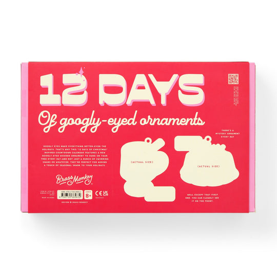 A pink and red box from Brass Monkey with white text reads Googly & Bright Holiday Ornament Countdown Calendar. The packaging features two ornament silhouettes and product info at the bottom.