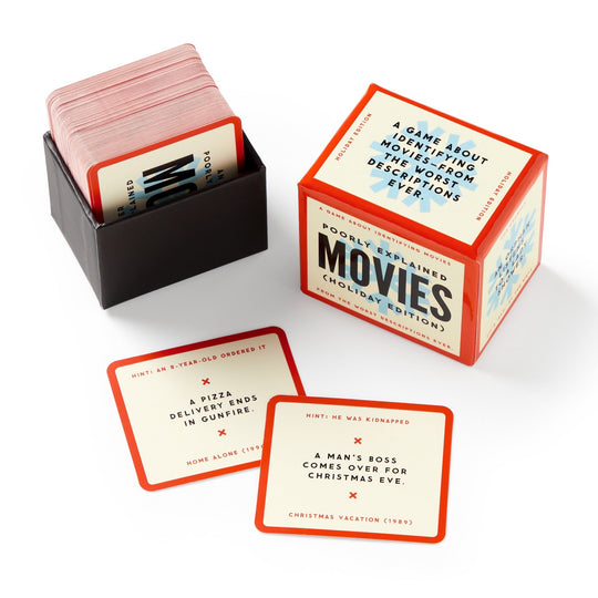 A box and stack of Brass Monkey’s Mini Poorly Explained Movies - Holiday Edition are shown, featuring cards with funny, vague holiday movie summaries and their answers at the bottom.