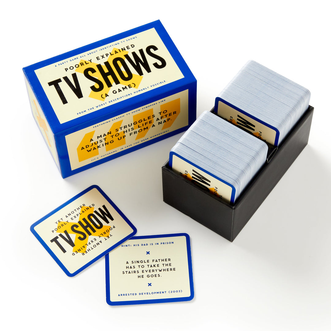 The Poorly Explained TV Shows Game by Brass Monkey is shown open with cards in a tray. Two cards are visible—one offers a vague pop culture clue and reveals Arrested Development (2003) as the answer.