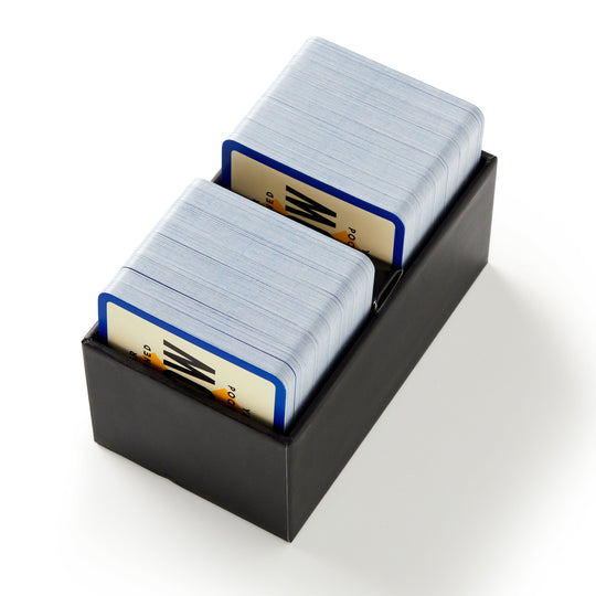 A black box from Brass Monkey containing two stacks of blue-edged cards with zigzag designs and "PO" text—an ideal party game for pop culture fans: the Poorly Explained TV Shows Game.