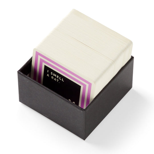A black box by Brass Monkey holds a stack of Useless Animal Trivia cards, with the top card showing a purple border and the text I SMELL A RAT—ideal for fans of odd animal facts or trivia.