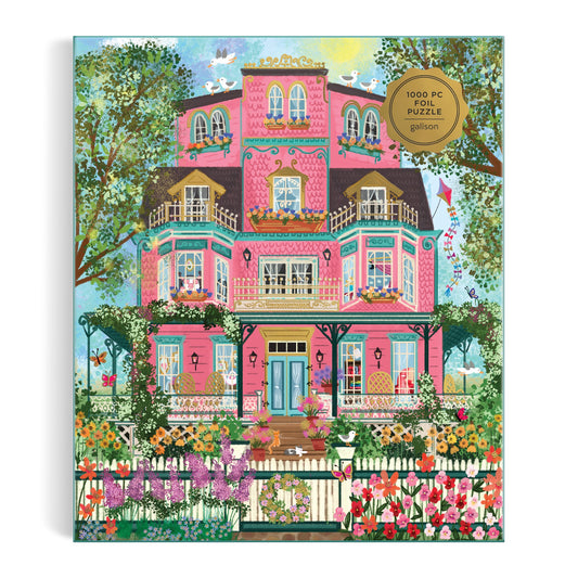 Colorful illustration of a pink Victorian mansion with balconies, gardens, and more by Joy Laforme features on the Joy Laforme Capeside Victorian 1000 Piece Foil Puzzle.