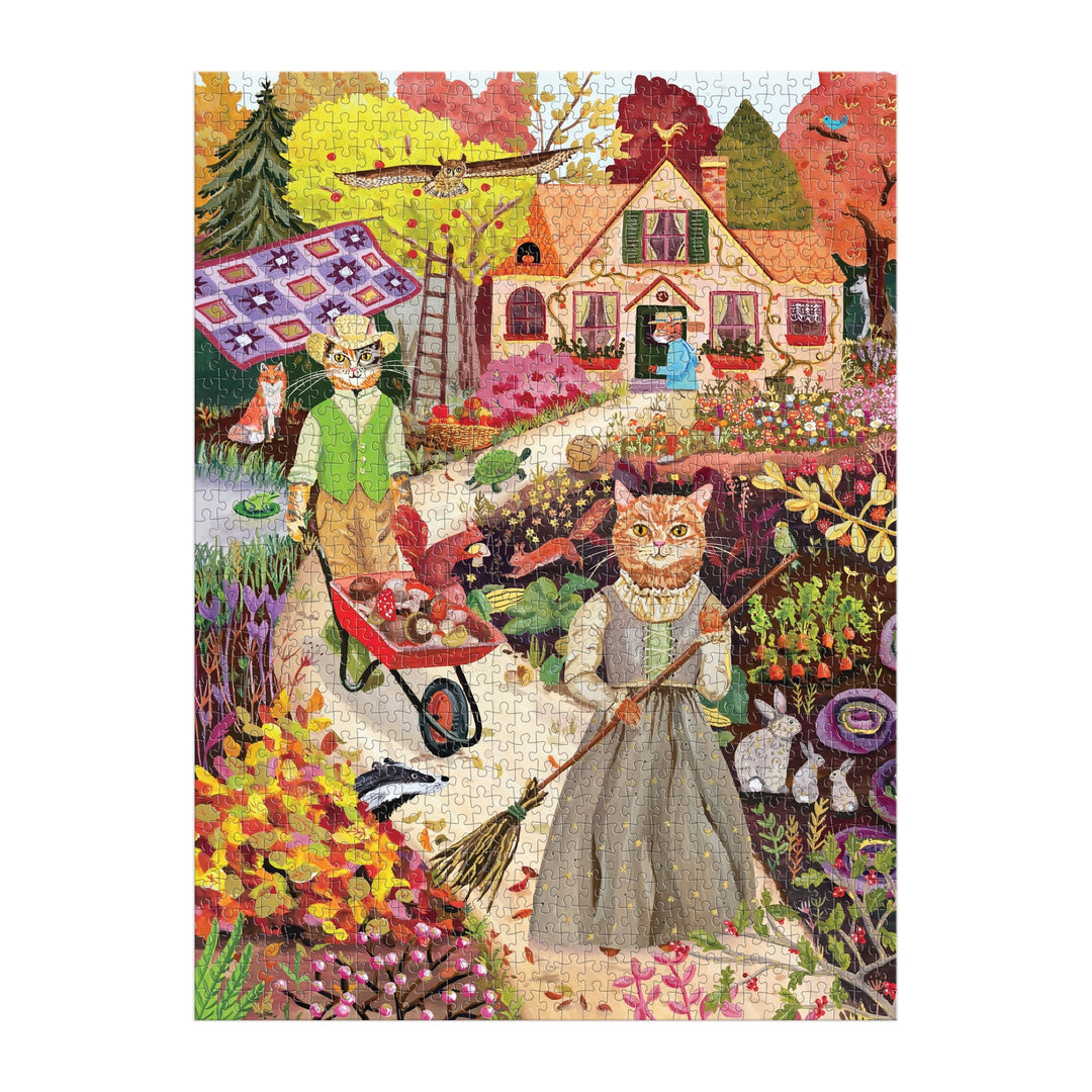 The Cottage Cats 1000 Piece Foil Puzzle by Anja Riebensahm depicts two cats in vintage attire gardening, with one pushing a wheelbarrow and the other sweeping, set against a fall-themed background with a house, woman at the door, and bird above.