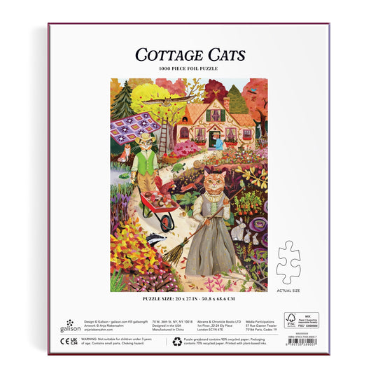 Back of the Anja Riebensahm Cottage Cats 1000 Piece Foil Puzzle box features illustrated cats in clothes enjoying autumn activities, set in a vibrant landscape with a cottage and garden. Text: Cottage Cats 1000 Piece Foil Puzzle.
