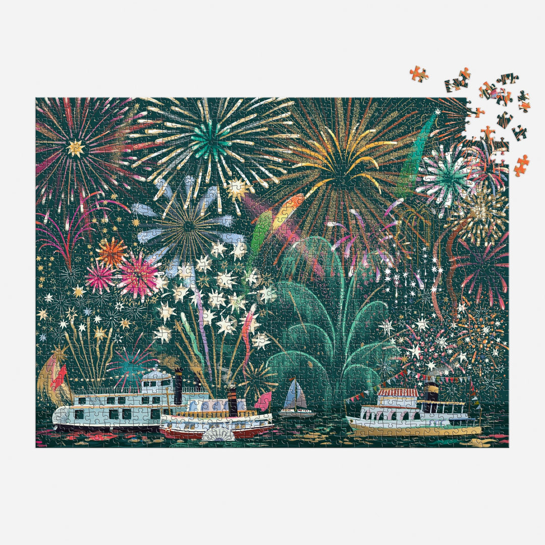 The Sarah Long Fireworks Jubilee 1000 Piece Foil Puzzle features vibrant fireworks over boats on a river at night, with a few pieces missing in the upper right corner.