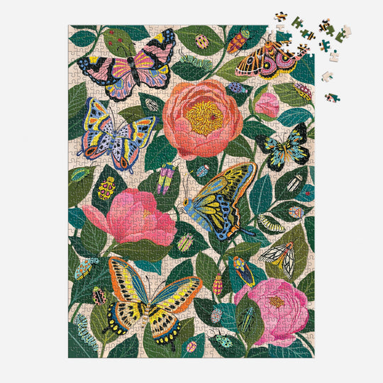 The Christine De Carvalho "Between the Blooms" 1000 Piece Foil Puzzle showcases vibrant butterflies and pink flowers with green leaves, with a few pieces missing in the top right corner.