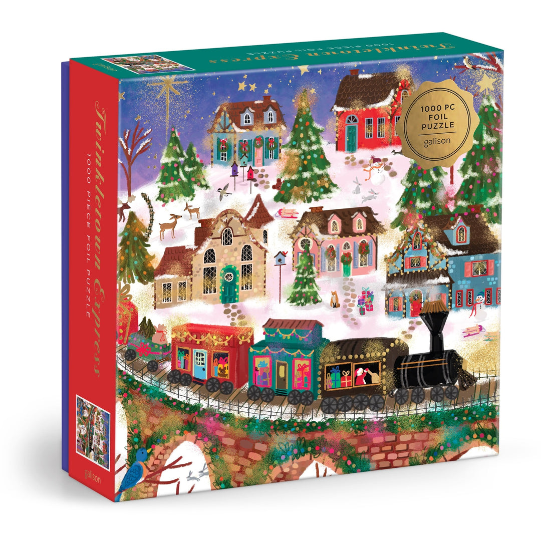 The Joy Laforme Twinkletown Express 1000 Piece Foil Puzzle features a festive winter village scene with decorated houses, snow-covered trees, reindeer, and a holiday train, all accented with colorful foil details.
