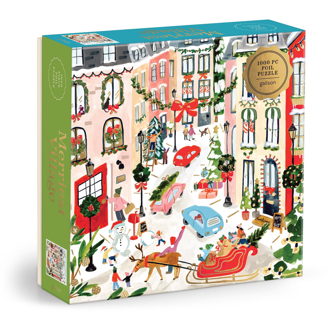 The Sabina Fenn Merriest Village 1000 Piece Foil Puzzle showcases a vibrant, snowy village street at Christmas, with people, cars, a sleigh, decorated trees, and festive garlands in a cheerful winter scene.