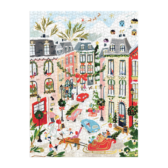 The Sabina Fenn Merriest Village 1000 Piece Foil Puzzle features an illustrated winter city scene with ice skaters, decorated buildings, snowy streets, and festive wreaths and garlands for a lively holiday vibe.