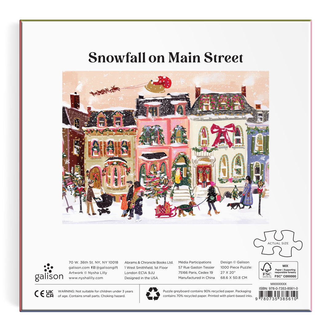 Enjoy Nysha Lilly’s Snowfall on Main Street 1000 Piece Foil Puzzle, featuring a festive street scene with shoppers in the snow, colorful foil-accented buildings, a large wreath, and Santa’s sleigh above.