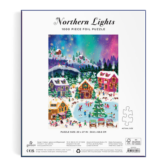 Back of the Joy Laforme Northern Lights 1000 Piece Foil Puzzle by Joy Laforme, showing a vibrant snowy village scene at night with people skating and skiing under northern lights. Finished puzzle measures 20 x 27 inches.