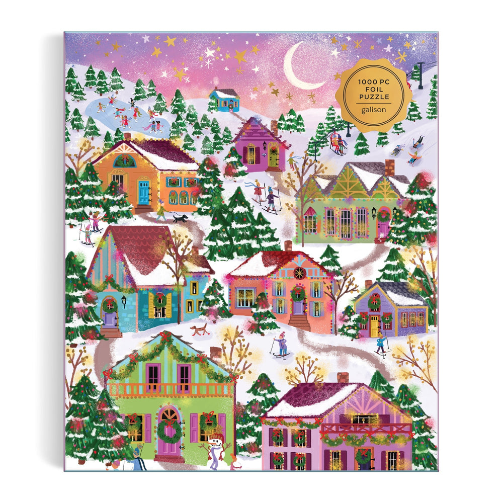 The Joy Laforme Snowcap Village 1000 Piece Foil Puzzle features a vibrant winter scene with snowy houses, trees, and skaters under a pink and purple evening sky, accented by shimmering foil details and a crescent moon.
