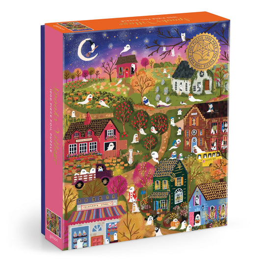 The Joy Laforme Spooky Village 1000 Piece Foil Puzzle features a vibrant nighttime scene with ghosts, pumpkins, orange-leaved trees, and a crescent moon on its box, plus a gold award seal in the top right corner.