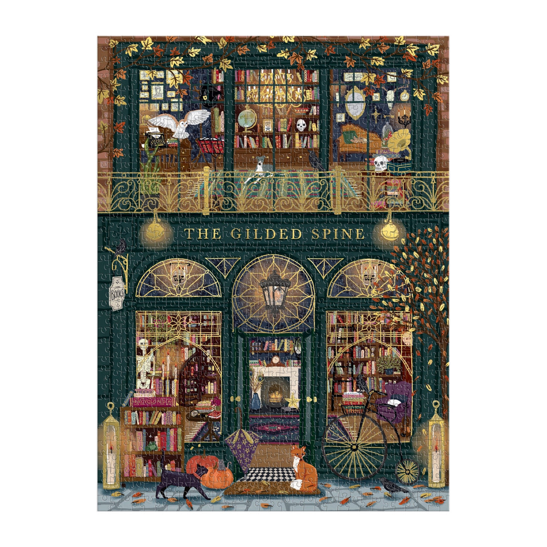 Sally Wilson’s The Gilded Spine 1000 Piece Foil Puzzle features a cozy two-floor bookshop filled with books, glowing lights, autumn leaves, and lounging cats in a warm, inviting scene with golden foil accents and intricate details.
