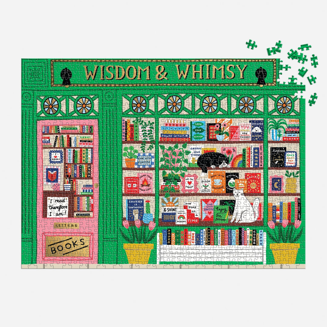 The Wisdom & Whimsy Bookshop 1000 Piece Foil Puzzle by Holly Maguire features a green bookstore with big windows, colorful books, a black cat on a shelf, a white cat on a bench, and missing puzzle pieces in the top right corner.