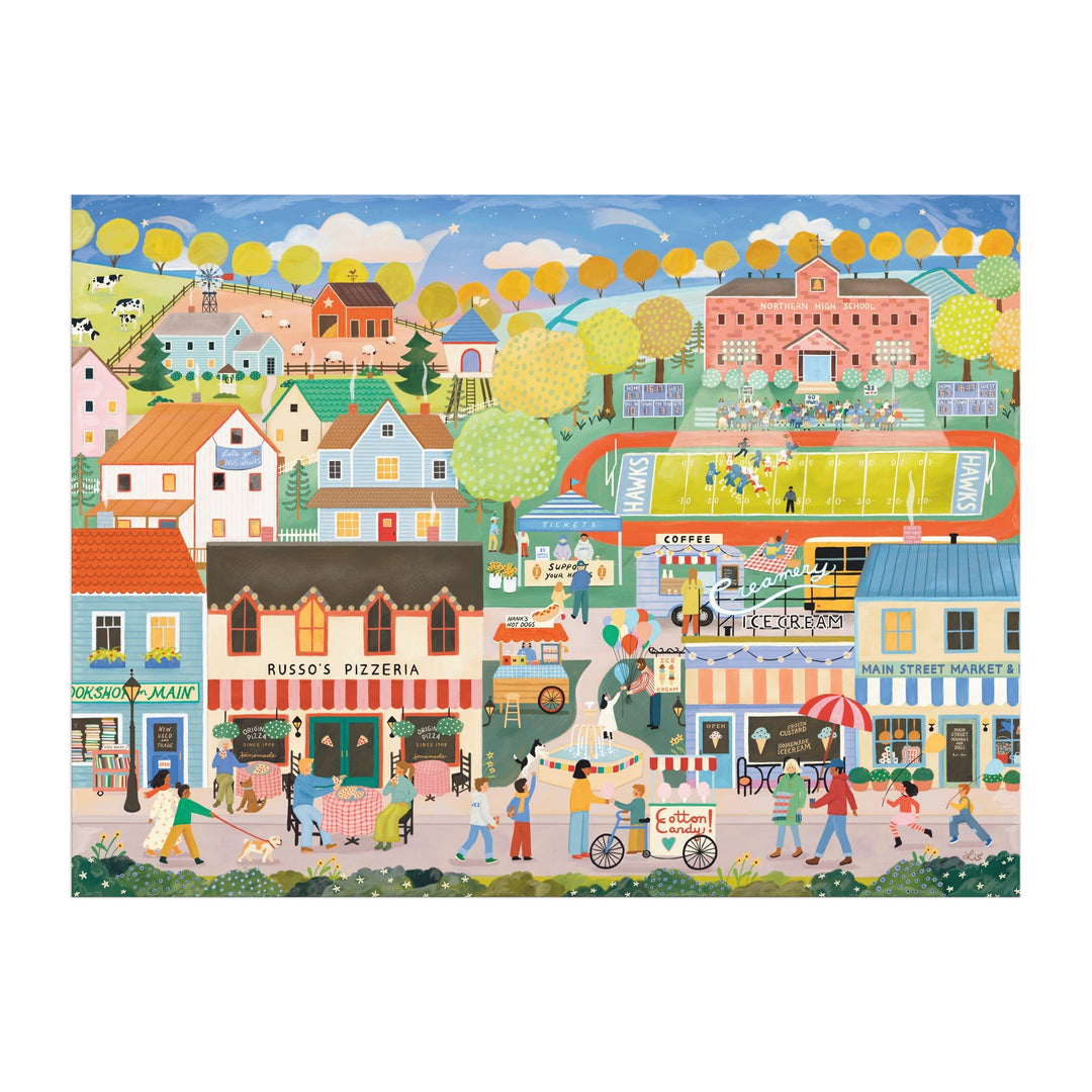 The Hometown Cheer 1000 Piece Puzzle by Elisabeth Dorrian features a vibrant small town scene with shops, restaurants, a pizzeria, people enjoying various activities, yellow-leaved trees, and a football game on a green field.