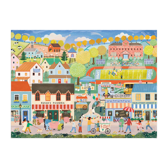 The Hometown Cheer 1000 Piece Puzzle by Elisabeth Dorrian features a vibrant small town scene with shops, restaurants, a pizzeria, people enjoying various activities, yellow-leaved trees, and a football game on a green field.