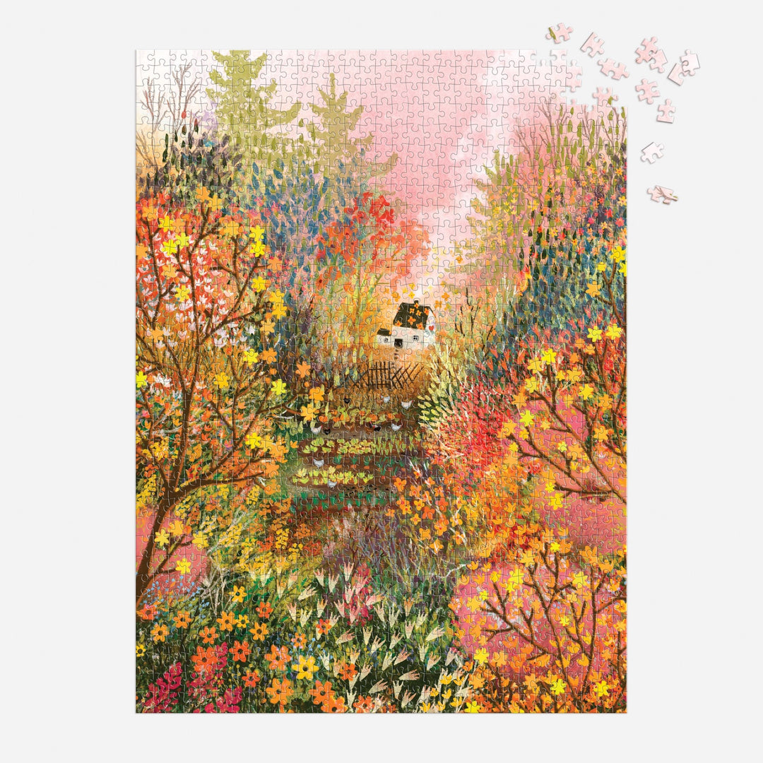 The Autumn in the Meadow 1000 Piece Puzzle by Laivi Põder features a cozy house among autumn trees and botanical details on a pink sky, with a few unplaced pieces in the top right corner.