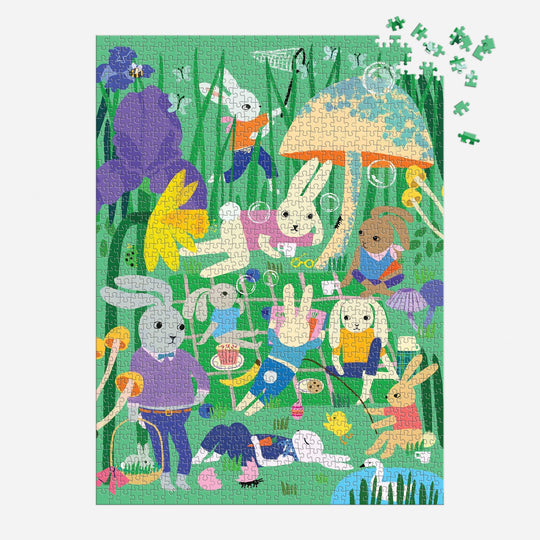 The Bunny Daydream 1000 Piece Puzzle by Anne Bentley features an illustration of rabbits and a bear having a tea party among large flowers and a giant mushroom, with some pieces at the top right still to be placed.