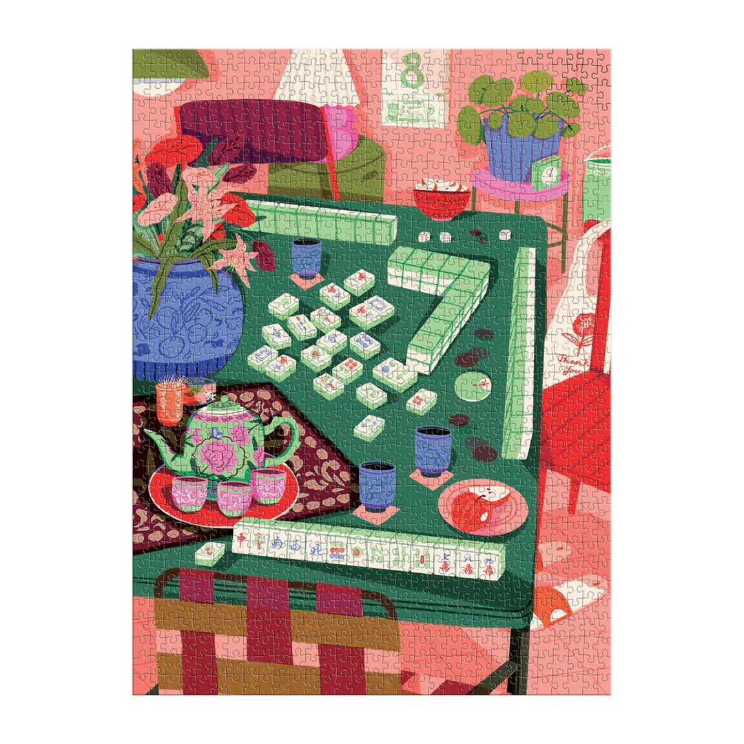 Mahjong Social 1000 Piece Puzzle by Paige Jung features a vibrant scene of a mahjong game on a green table, surrounded by tea, cups, flowers, plants, and cozy pink and red decor.