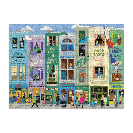 The Main Street Books 1000 Piece Puzzle by Anne Bentley features a colorful, illustrated city street filled with whimsical storefronts, lively people, bookshops, and fantastical details like dragons, dinosaurs, giant cats, and birds.