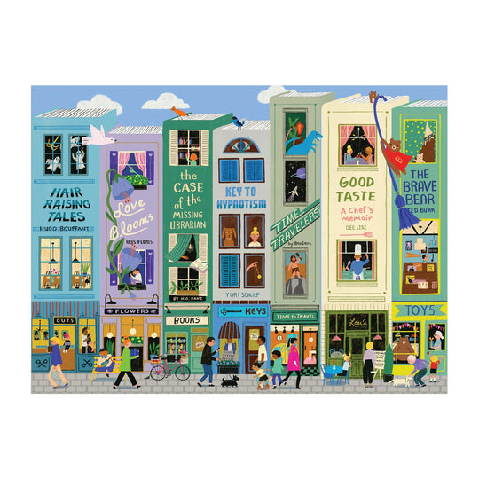 Colorful illustration from Anne Bentley’s Main Street Books 1000 Piece Puzzle: a lively city street with shops, apartments, and signs like “Time Travelers,” “Good Taste,” and “The Brave Bear.” People stroll while cats and birds perch on window sills.