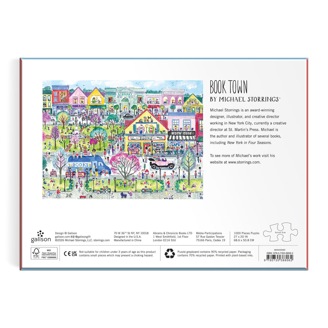 Vibrant illustration of a lively town centered on a bookstore, with people walking and reading among pastel buildings; text highlights the Michael Storrings Book Town 1000 Piece Puzzle by Michael Storrings, perfect for book lovers.