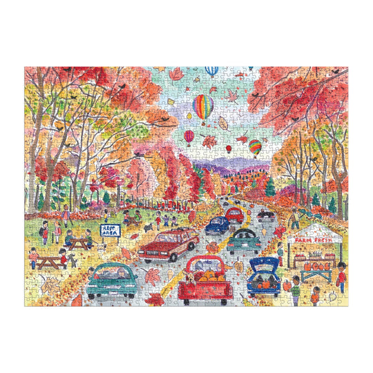 The Michael Storrings Leaf Peeping 1000 Piece Puzzle by Michael Storrings showcases cars, people enjoying outdoor fun, picnic tables, a food stand, and hot air balloons floating over scenic autumn foliage.