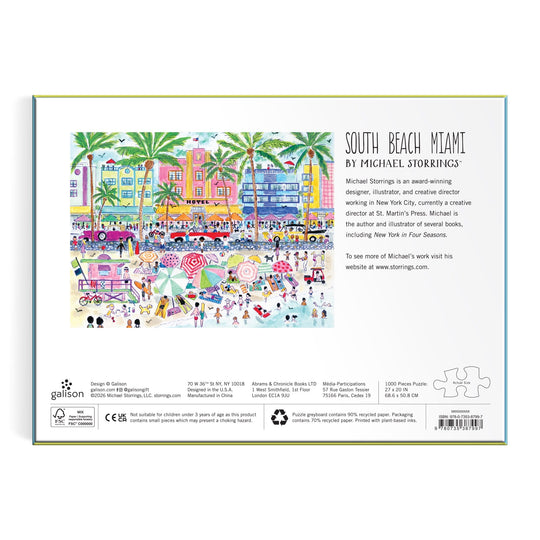 The Michael Storrings South Beach Miami 1000 Piece Puzzle by Michael Storrings features a vibrant illustration of Art Deco buildings, palm trees, and lively beach scenes with swimmers, sunbathers, umbrellas, and a bustling boardwalk.