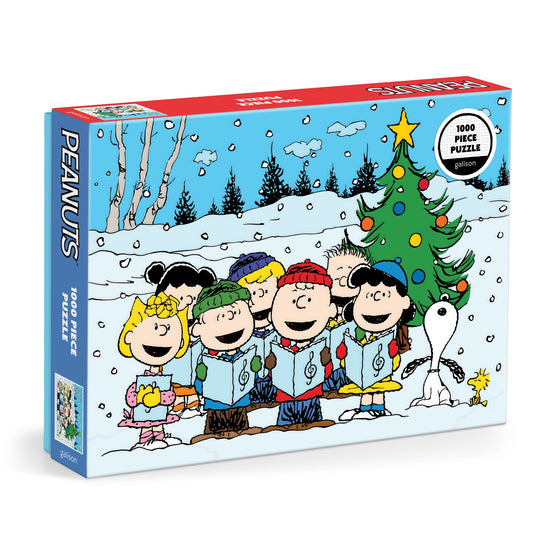 The Peanuts Christmas Caroling 1000 Piece Puzzle by Peanuts Worldwide, LLC features beloved characters caroling by a decorated tree in a snowy, festive setting.