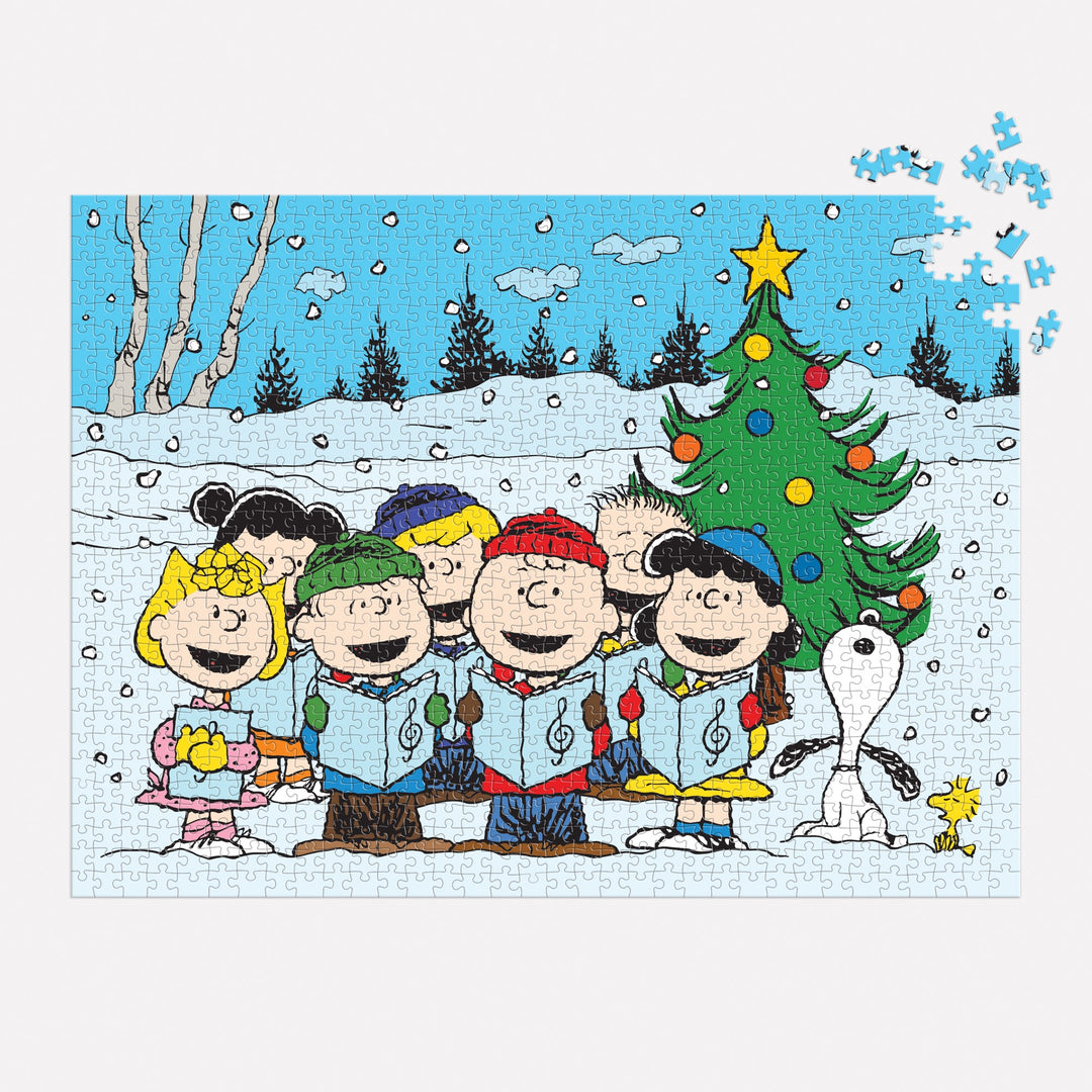 The Peanuts Christmas Caroling 1000 Piece Puzzle by Peanuts Worldwide, LLC features beloved characters singing by a snowy tree with Snoopy and Woodstock. A few pieces are missing from the top right corner.